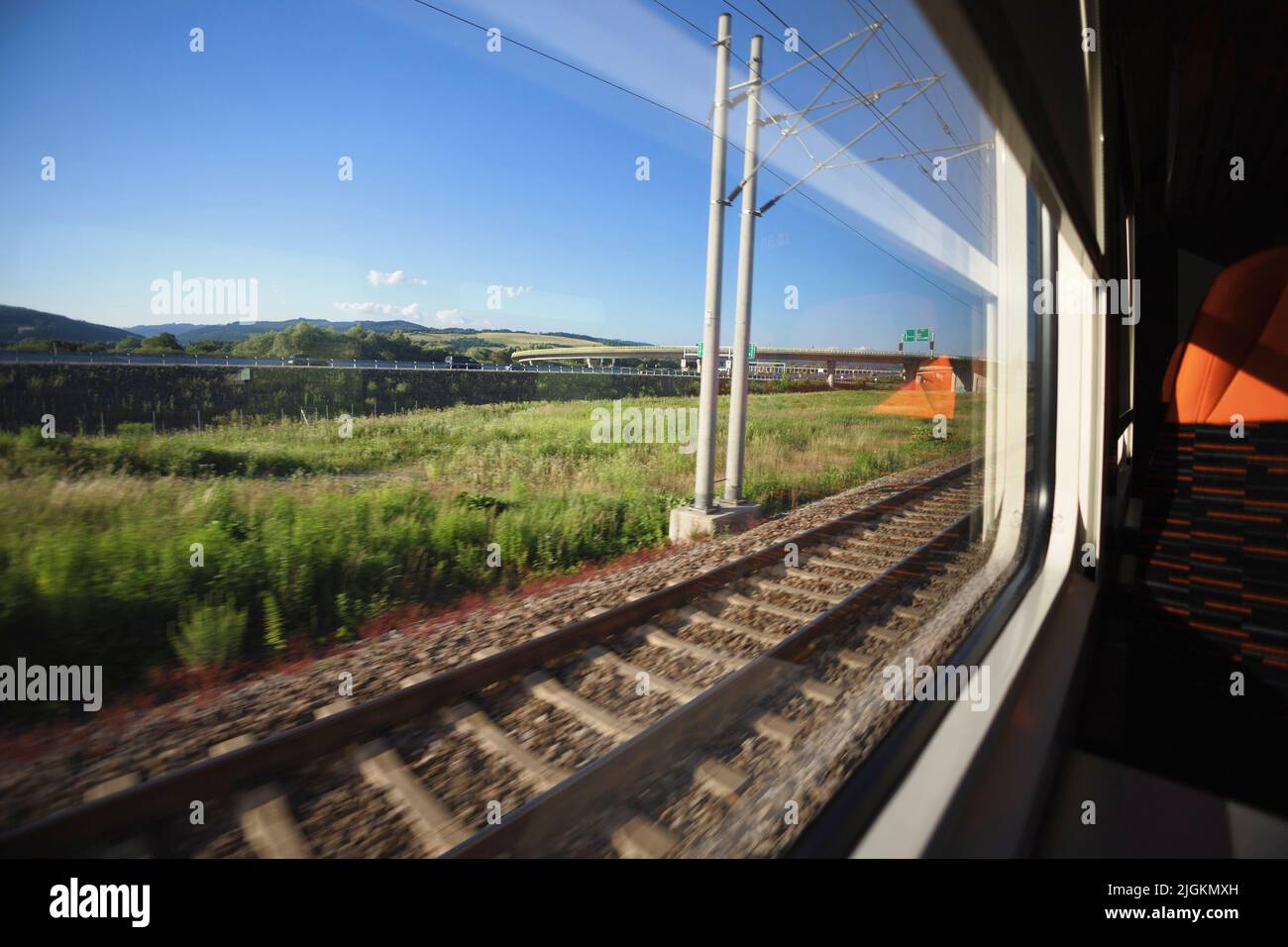 Mit dem Zug fahren und die Landschaft vom Fenster aus beobachten. Anreise mit öffentlichen Verkehrsmitteln. Dynamische Aufnahme mit Bewegungsunschärfe, Weitwinkelverzerrung und Fokus Stockfoto