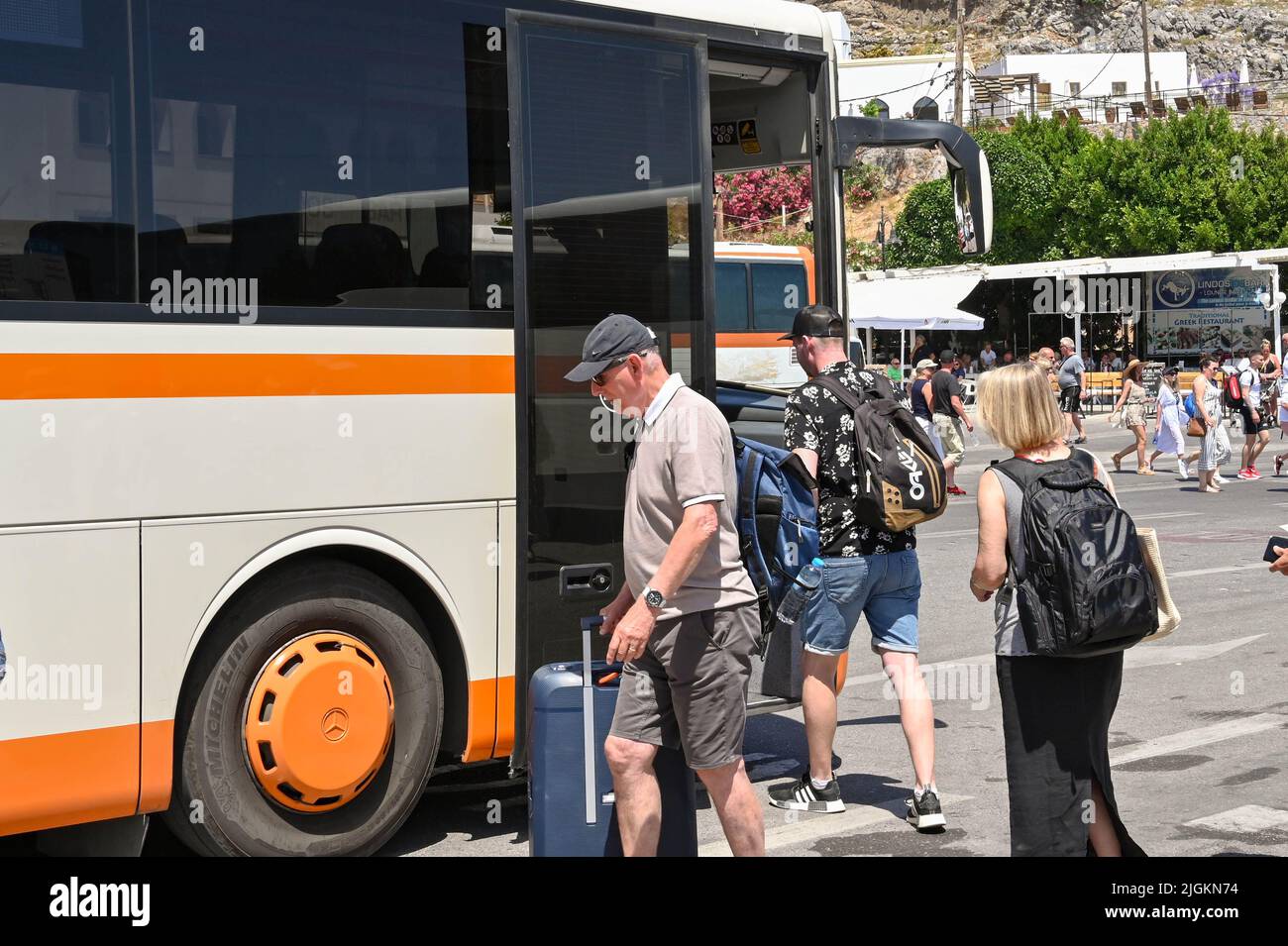 Lindos, Rhodos, Griechenland - Mai 2022: Menschen, die einen öffentlichen Bus an der Bushaltestelle der Stadt nehmen Stockfoto