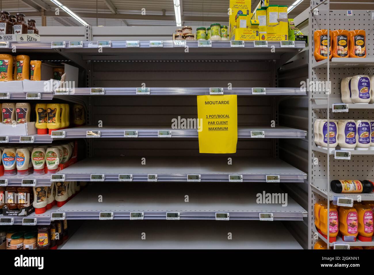 Ardres, Frankreich - 26. Juni 2022: Leere Regale in einem französischen Supermarkt. Es gibt nur wenige Senflinge. Auf dem Schild steht: „Nur ein Glas pro Kunde“ Stockfoto