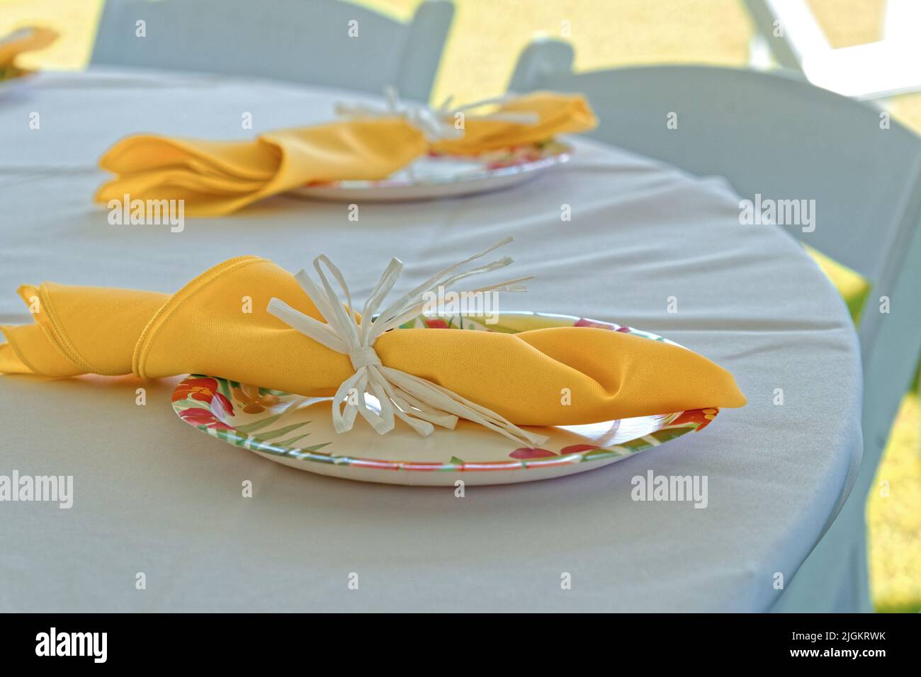 Gelbe Servietten in Pappteller auf weißem Tischdecke Stockfoto