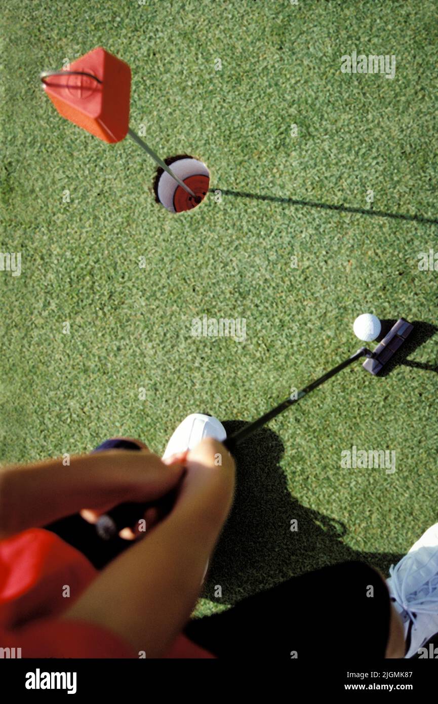 Ein Golfer richtet sich für einen Putt auf dem Übungsgrün ein. Stockfoto