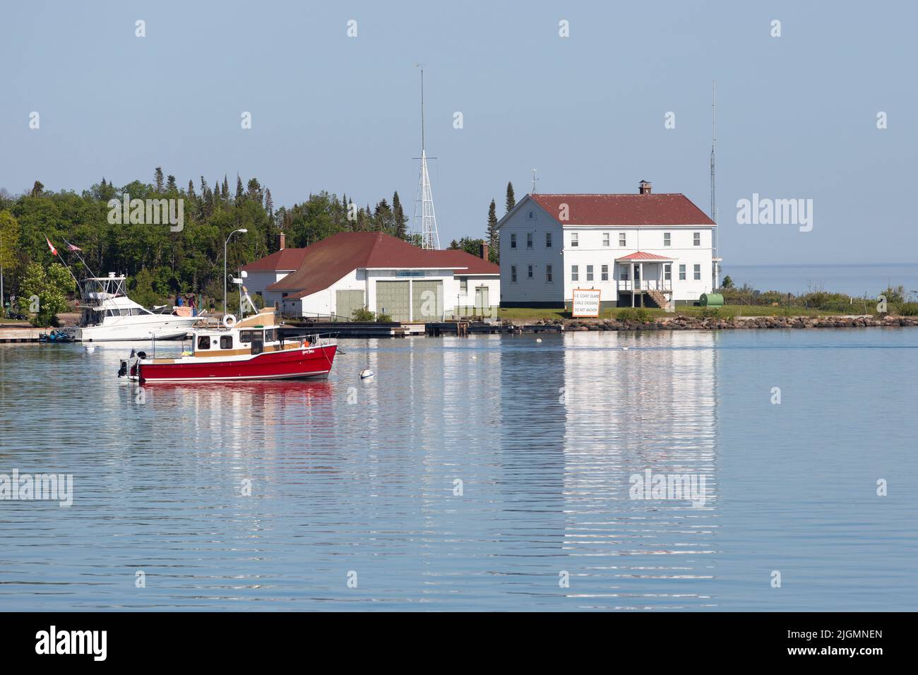 Chartern Sie Fischerboote und die 1928 Great Lakes Station House of U.S. Coast Guard Station North, Lake Superior im Hafen von Grand Marais, Minnesota Stockfoto