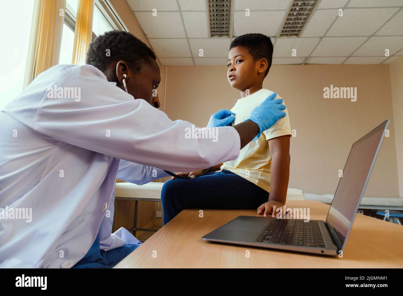 afroamerikanischer Mann Kinderarzt Arzt mit Stethoskop zur Untersuchung kleiner Junge von Krankheit im Büro im Krankenhaus. Medizinische und gesunde li Stockfoto