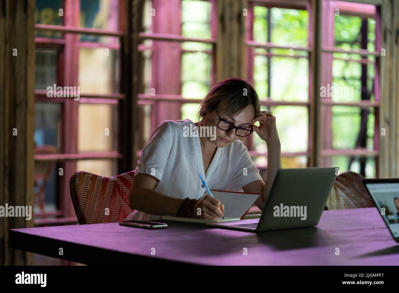 Fokussierte, nachdenkliche junge Studentin, die mit einem Laptop sitzt, kaukasische Dame, die im Coworking Space arbeitet Stockfoto