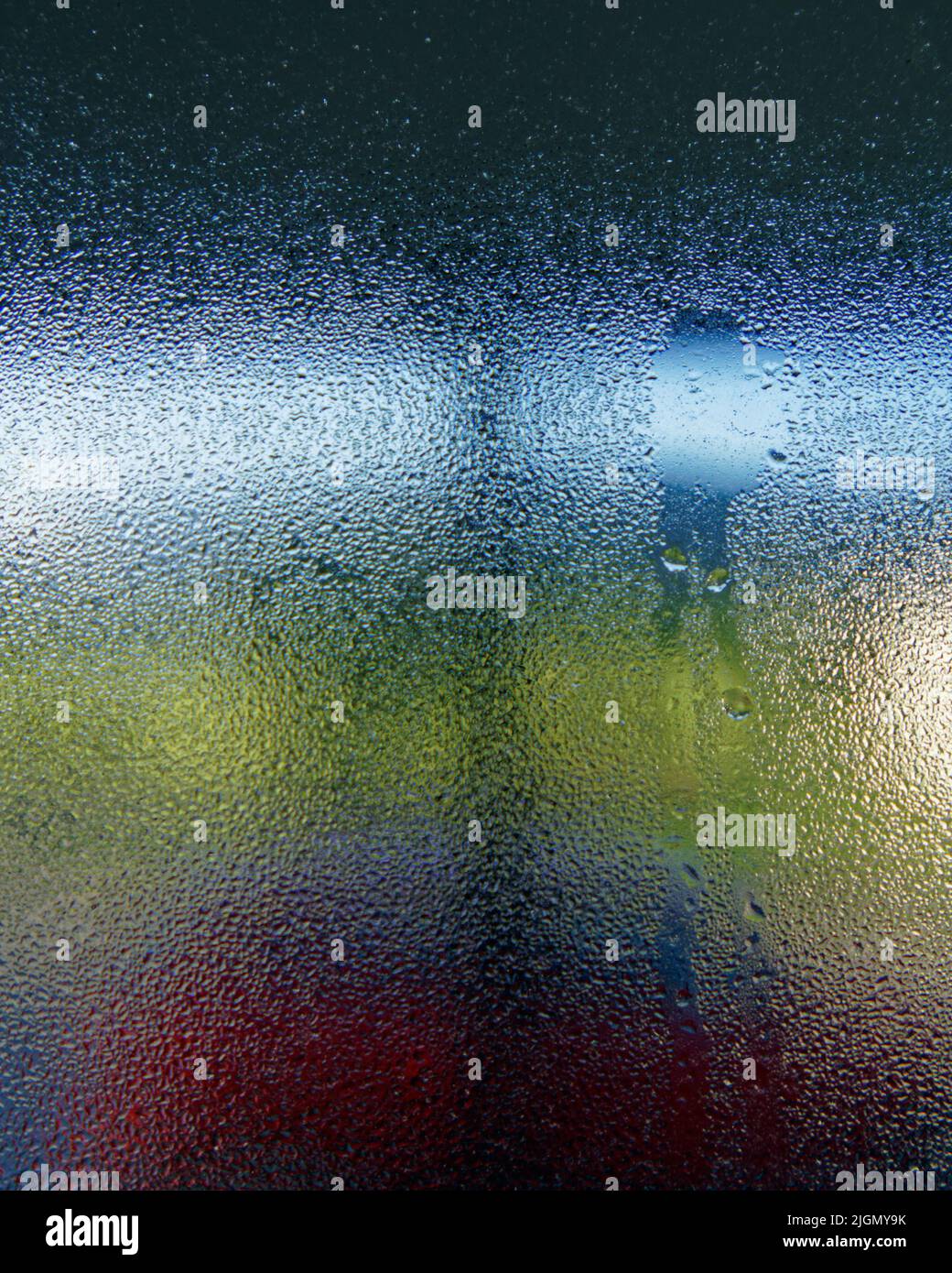 Kondenswasser, das in einem kalten, feuchten Haus durch das Innere eines Fensters läuft. Stockfoto