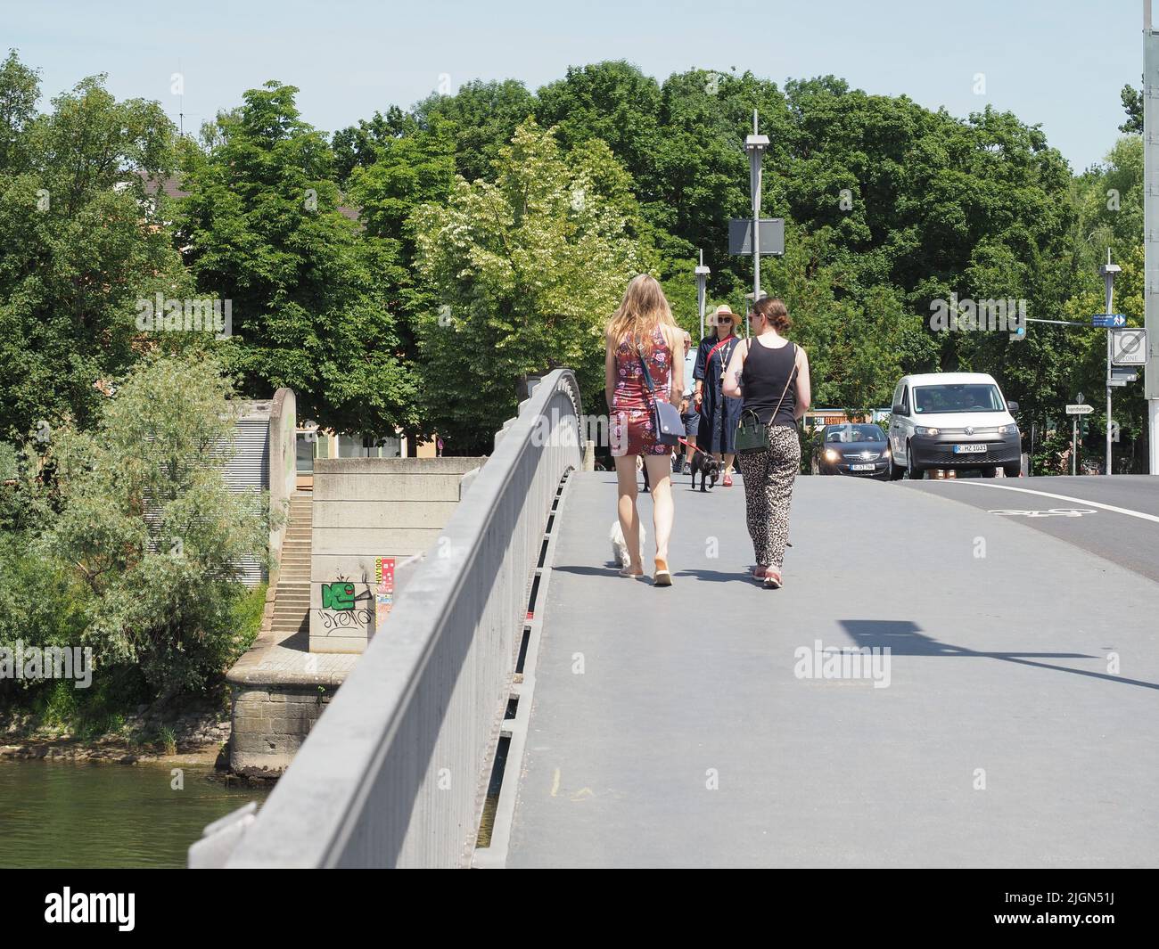 REGENSBURG, DEUTSCHLAND - CA. JUNI 2022: Menschen überqueren die Eiserne-Brücke über die Donau Stockfoto