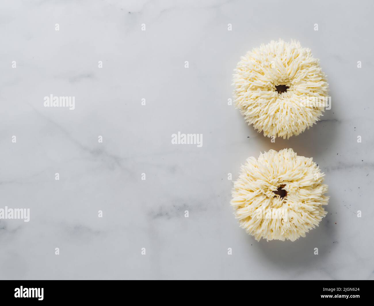 Shag Donuts auf weißem Marmor Hintergrund. Ungewöhnliche trendige Donuts mit Vanillecreme. Speicherplatz kopieren. Ansicht von oben oder flach liegend. Stockfoto