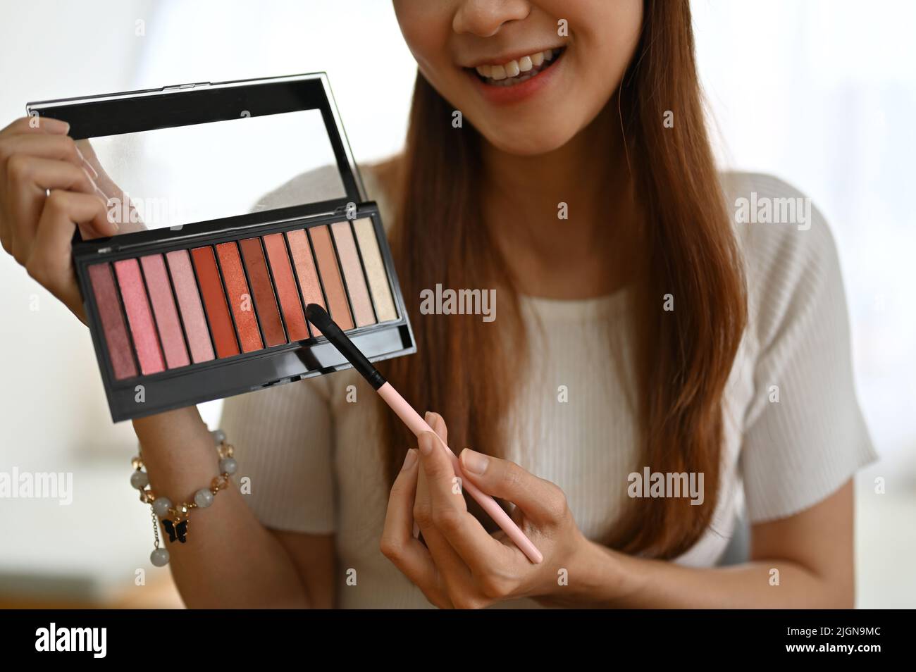 Attraktive, tausendjährige asiatische Beauty-Bloggerin zeigt eine Lidschatten-Palette, prüft Kosmetikprodukte und macht ein Make-up-Video. Stockfoto