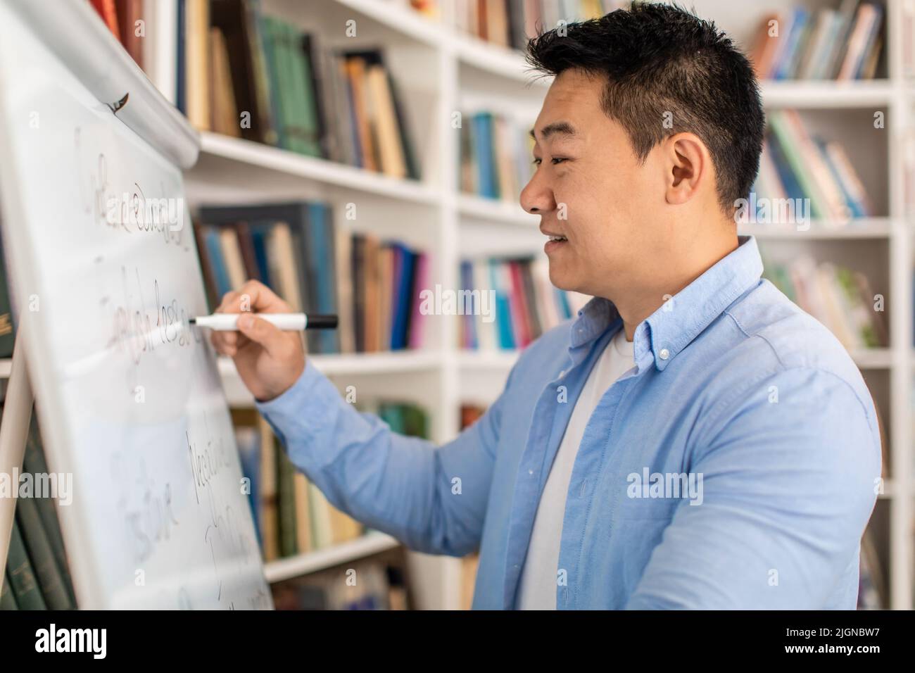 Glücklich Koreanisch Männlich Lehrer Schreiben Auf Whiteboard Stehen Im Klassenzimmer Stockfoto