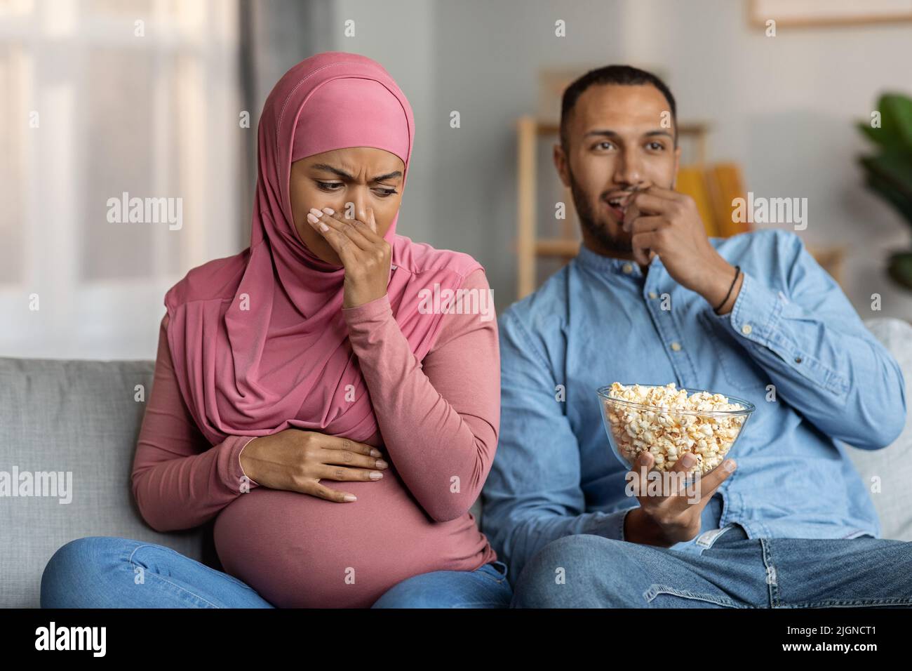 Geruchsbildung Während Der Schwangerschaft. Schwarze, Schwanger Muslimische Frau Angewidert Vom Popcorngeruch Stockfoto