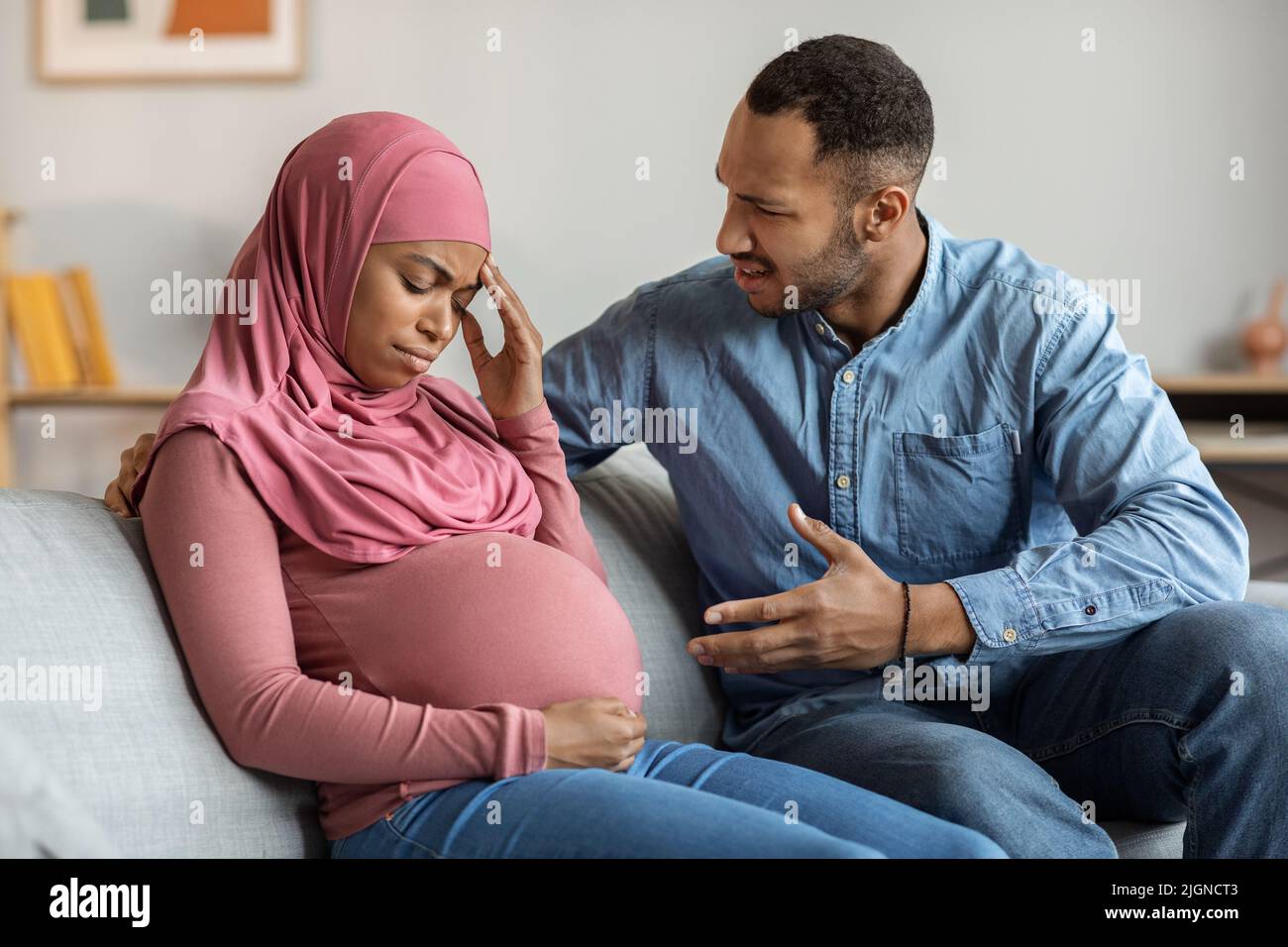Psychologischer Missbrauch. Aggressiver schwarzer Mann, der zu Hause mit einer schwangeren muslimischen Frau streitet Stockfoto