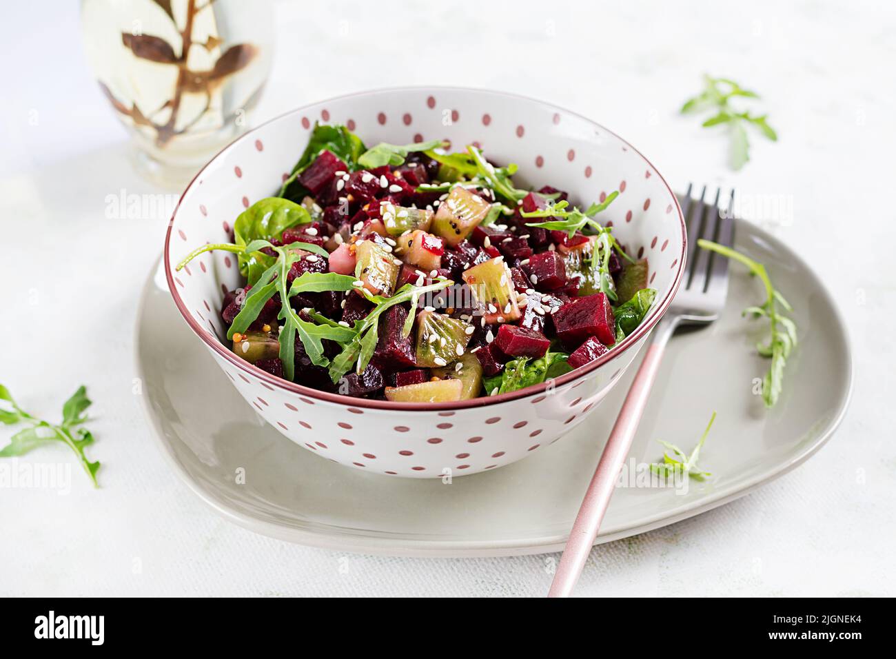Schüssel mit Salat mit gebackenen Rote Beete, Kiwi, Spinat, Rucola und Dressing Senf, Öl. Stockfoto