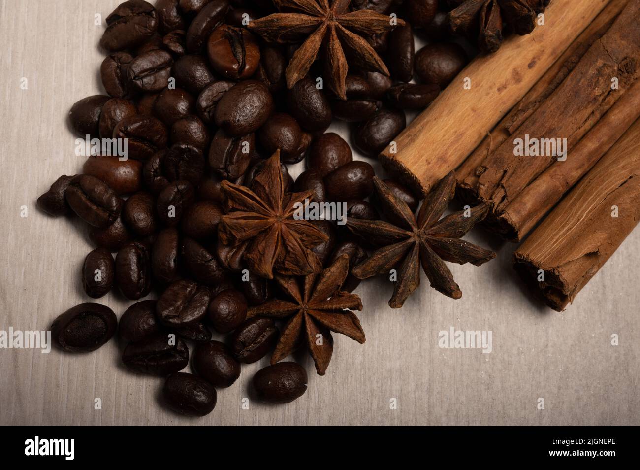 Zimt, Sternanise, Kaffeebohnen aus der Nähe auf einem hellen Holzhintergrund, aufgenommen von oben Stockfoto