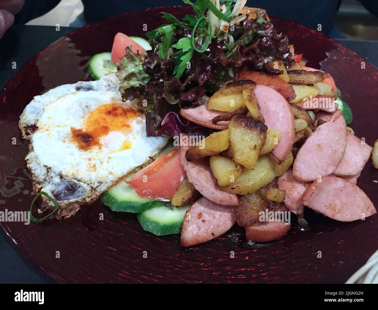 Gebratene Schnittkartoffeln mit gebratenen Würstchen mit sonnigen ...