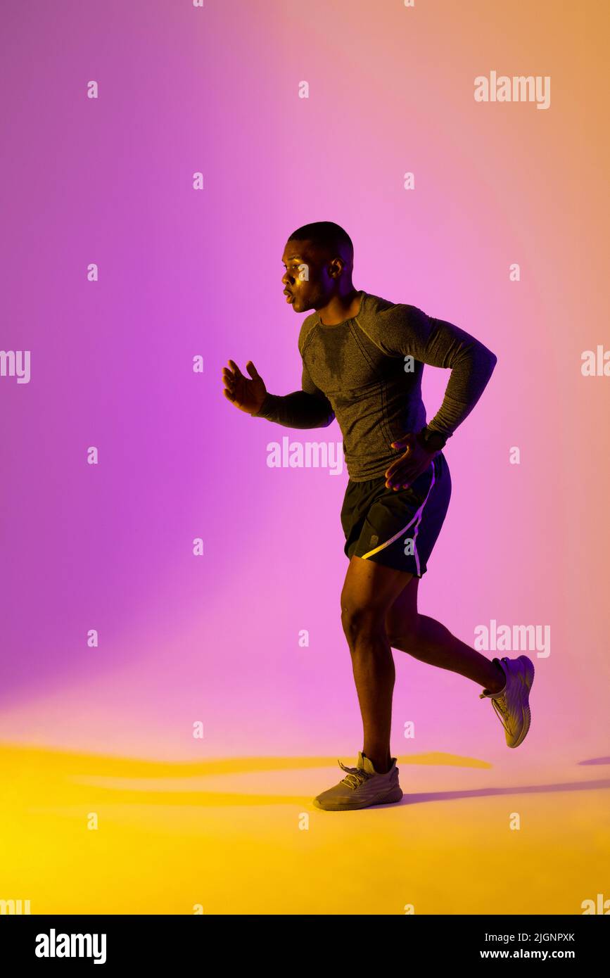 afroamerikanischer Läufer mit Sportswear über rosa Beleuchtung Stockfoto