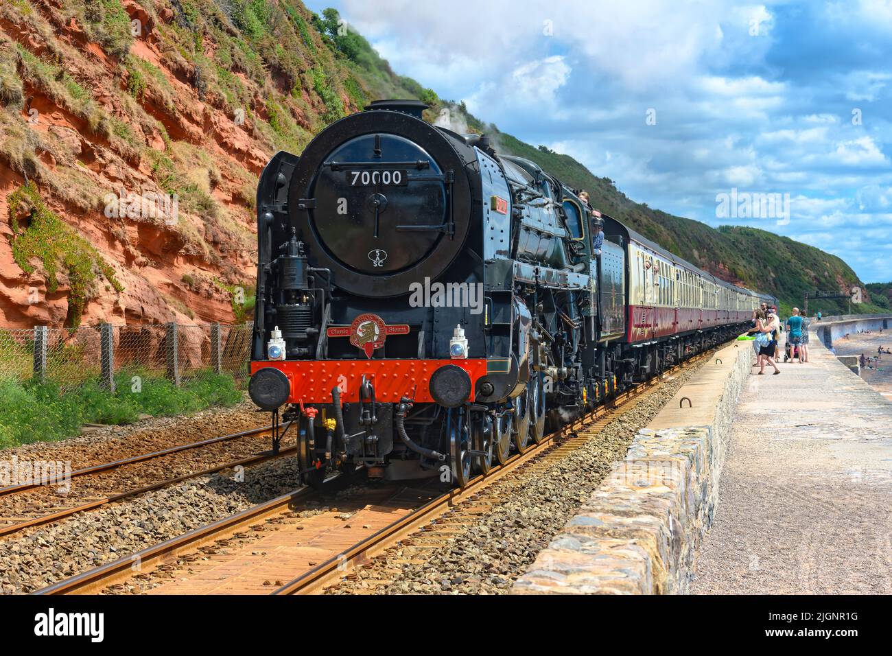 Die Dampflokomotive 70000 Britannia schleppt den Riviera Express an der Meeresmauer Teignmouth South Devon UK vorbei Stockfoto