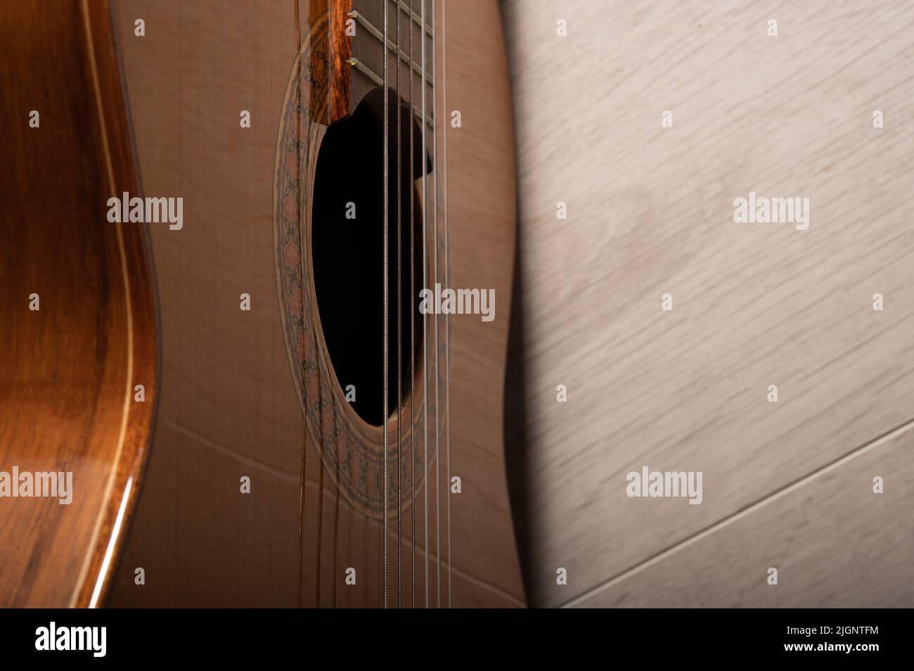 Klassische Gitarre Sound Loch und Saiten aus der Nähe auf einem hellen Holz Hintergrund Stockfoto