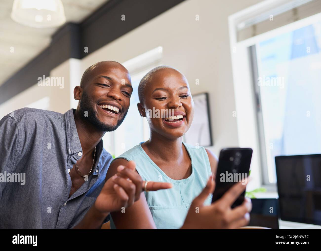 Zwei schwarze Kollegen sehen sich ein lustiges Video am Handy-Point an und lachen Stockfoto