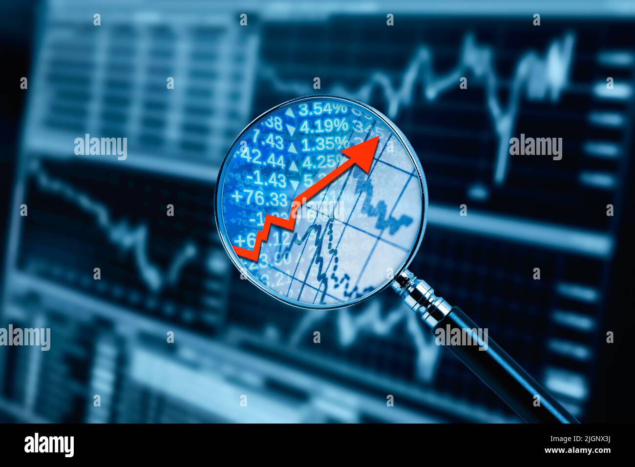Lupe mit rotem Pfeil und Finanzdaten und Monitor im Hintergrund Stockfoto