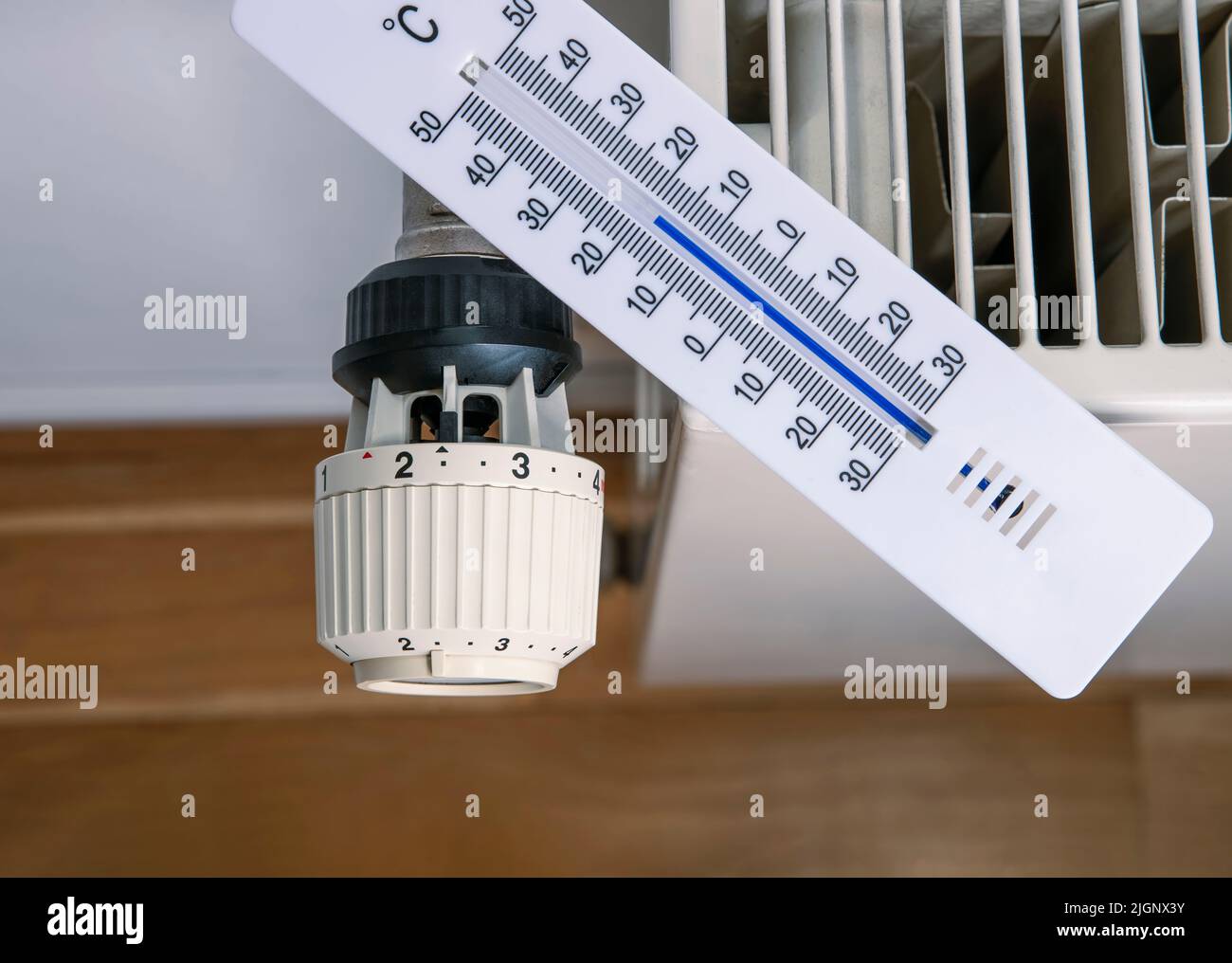 Das Thermometer liegt auf einem Heizkörper, um die Raumtemperatur zu messen. Stockfoto