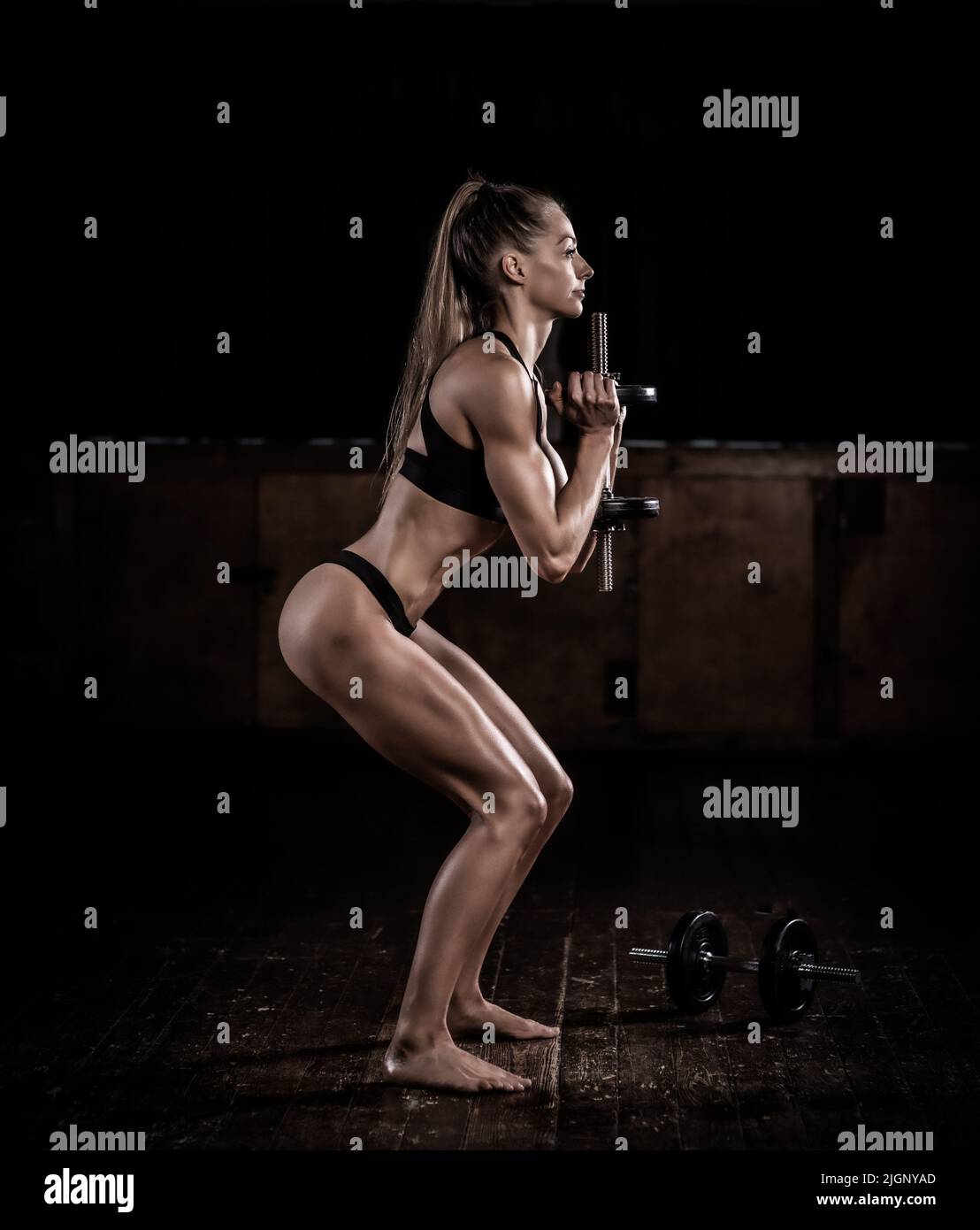 Weibliches Fitnessmodell mit getöntem Körper, das mit Gewichten trainiert, Großbritannien Stockfoto