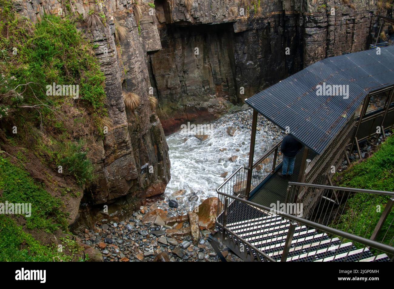 Maingon Bay Australia, Blick über eine Treppe und Wasser, das durch den Eingang einer bemerkenswerten Höhle rauscht Stockfoto