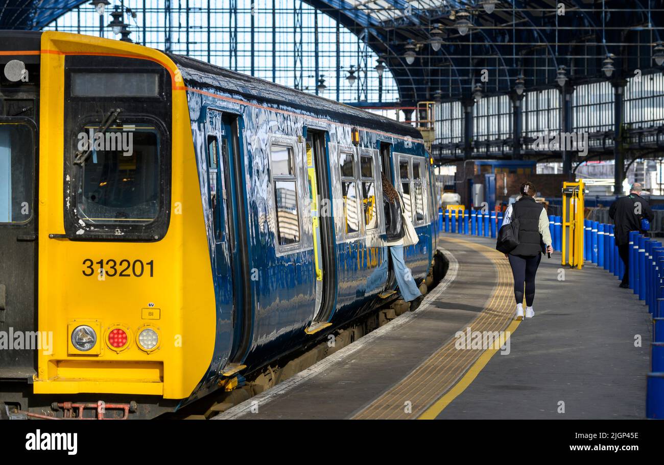 Passagiere, die in einem Zug der British Rail-Klasse 313 in der Southern Livery, Brighton Railway Station, England, einsteigen. Stockfoto