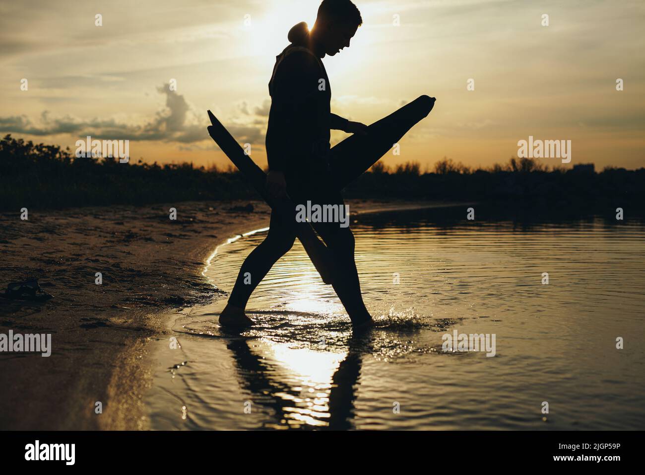 Silhouette Aufnahme eines männlichen Tauchers, der bei Sonnenuntergang Speerfischen geht. Abenteuerlicher junger Mann, der mit seiner Speerfischerei ins Meerwasser geht. Stockfoto