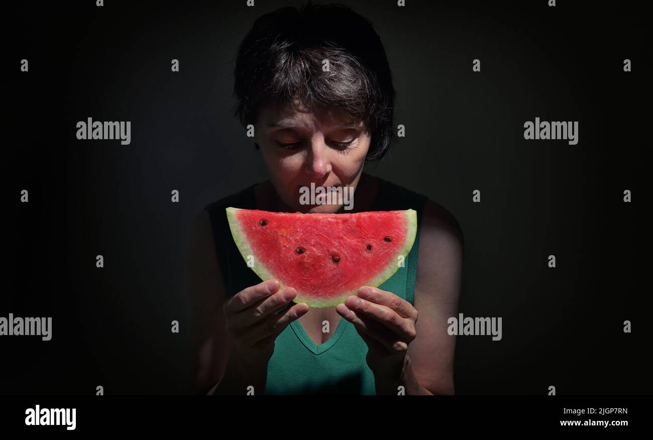Frau, die im Studio eine Schicht Einer roten Wassermelone hält Stockfoto