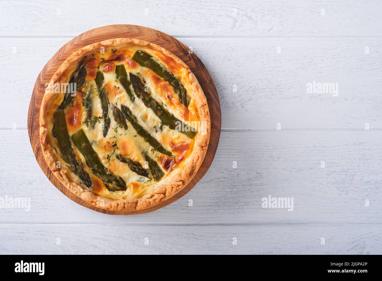 Quiche. Hausgemachte Spargelpastete oder Quiche mit Käse und Spinat auf weißem Holztisch Hintergrund. Traditionelles Französisches Quiche. Draufsicht. Stockfoto