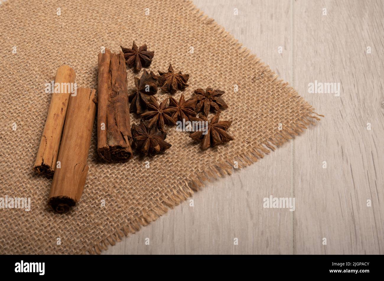 Zimt, Sternanise auf einem hessischen Tuch mit hellem Holzhintergrund Stockfoto