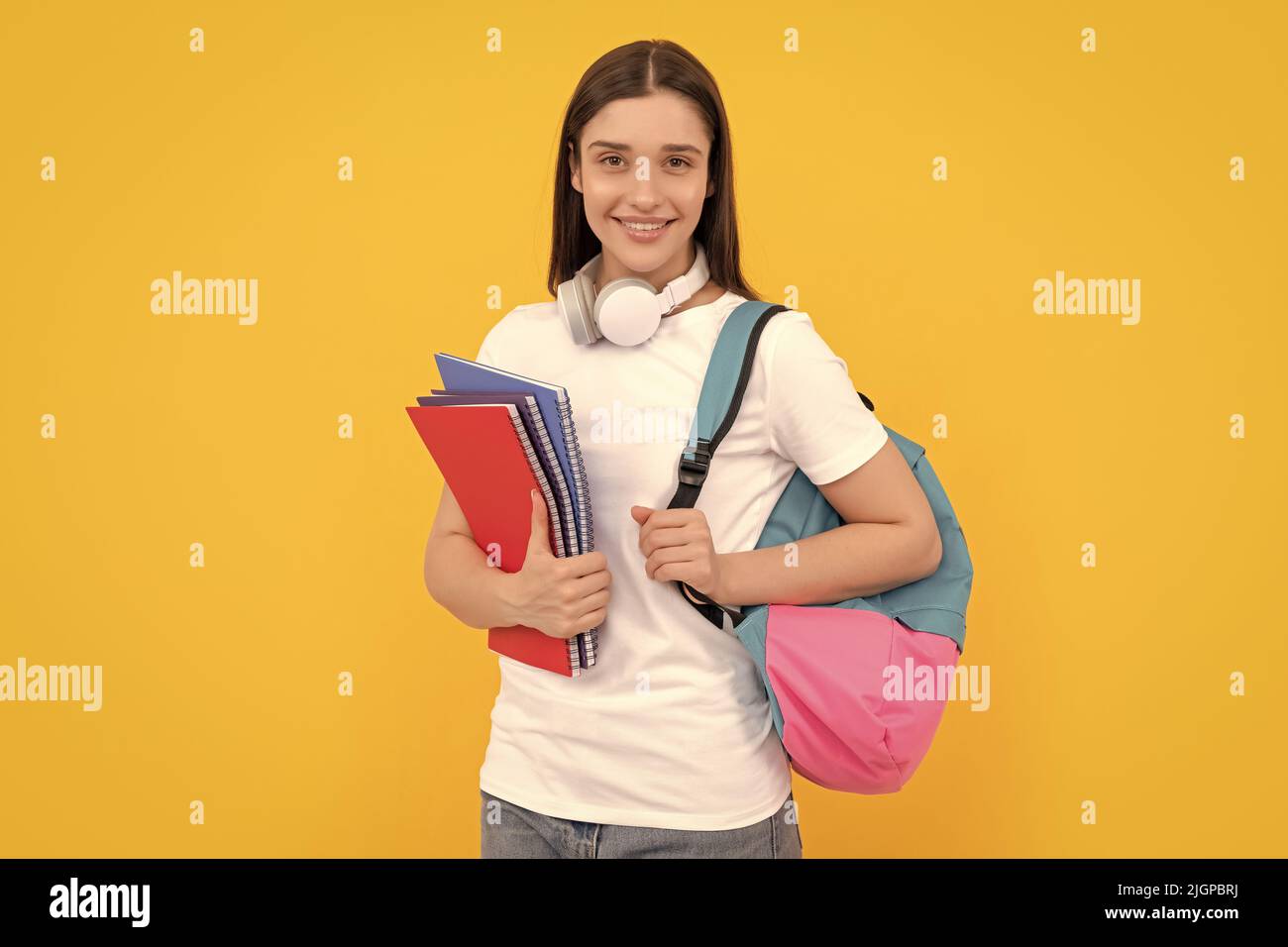 Lächelnde Dame in den Kopfhörern halten Copybook tragen Rucksack, Wissen Stockfoto