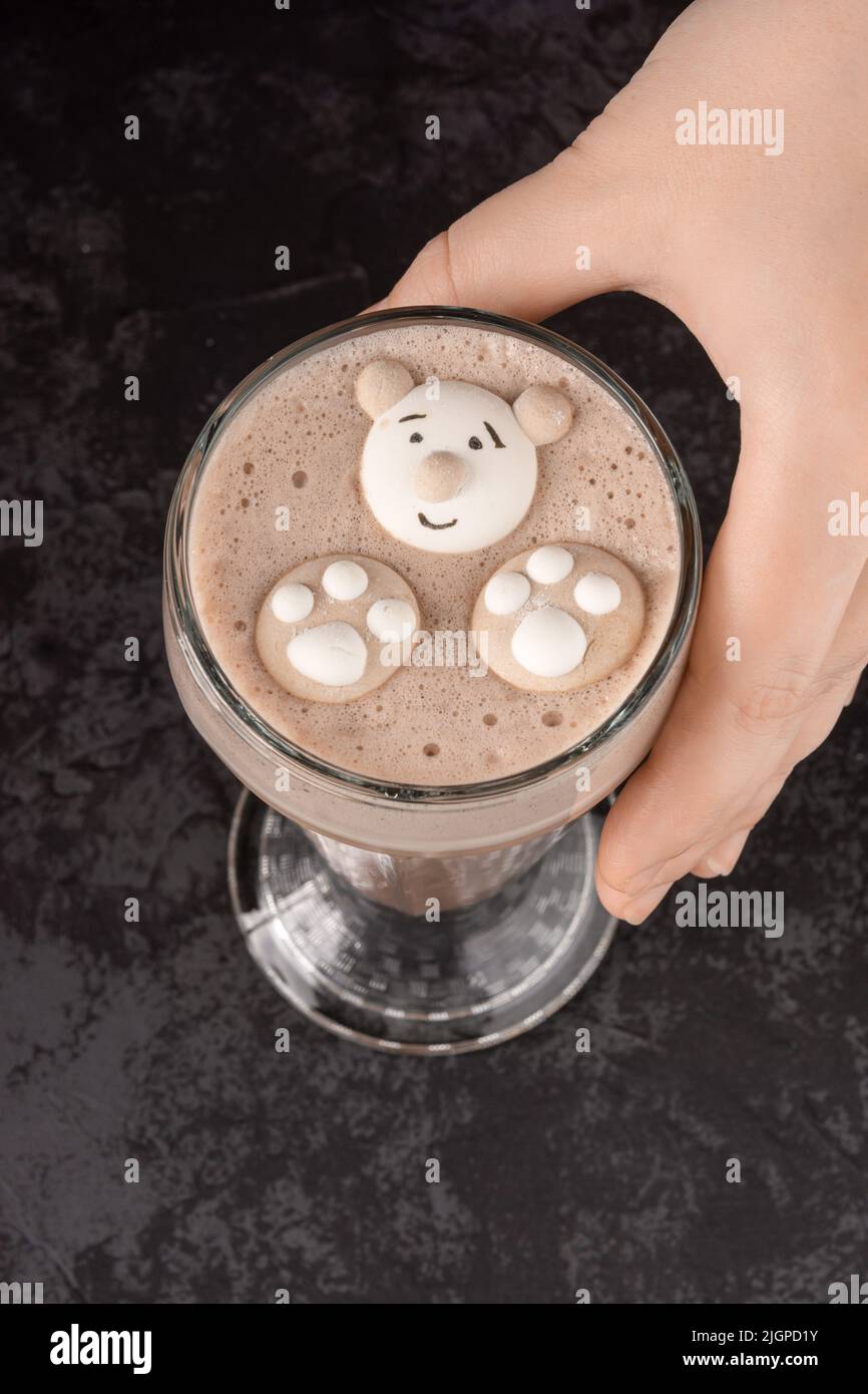 In einem Café auf dunklem Hintergrund ist ein Kakaogetränk mit lustigen Keksen dekoriert Stockfoto
