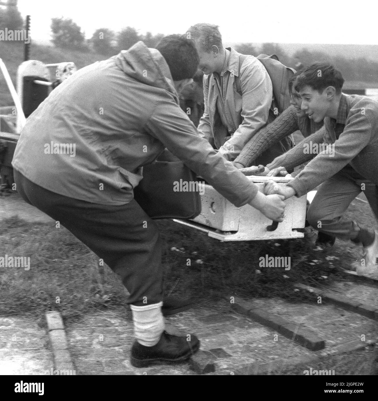 1960s, historisch, Jugendliche, die ein Holztor schieben, um die Schleuse an einem Kanal zu öffnen, England, Großbritannien. Ein Schloss ist ein wasserdichtes Becken und Tore an jedem Ende der Schleusenkammer ermöglichen es den Booten ein- und auszufahren. Torschlösser stammen aus dem 10.. Jahrhundert und dem Großen Kanal Chinas. Stockfoto