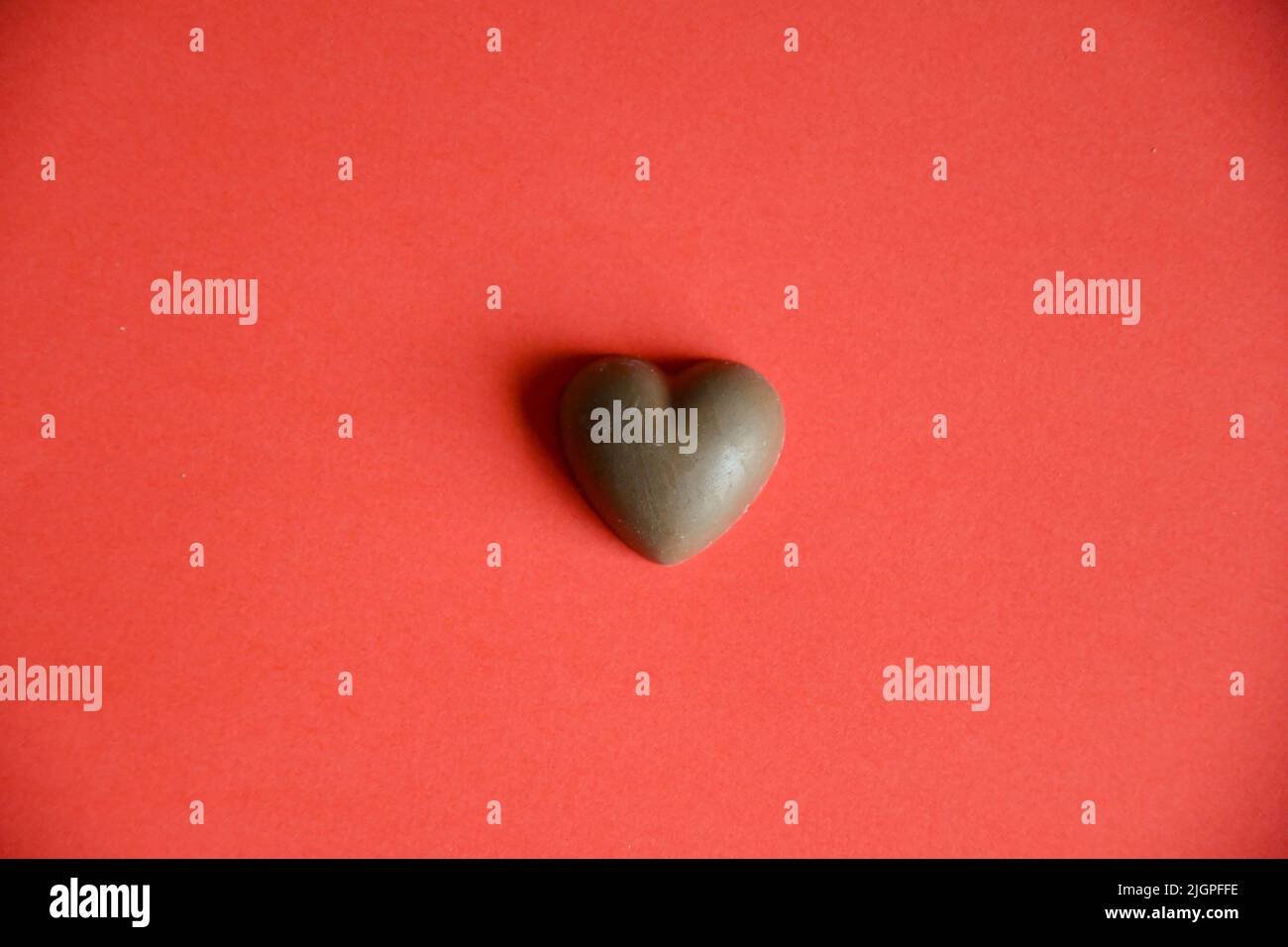 Foto von Schokolade Süßigkeiten Herz auf rotem Hintergrund Stockfoto