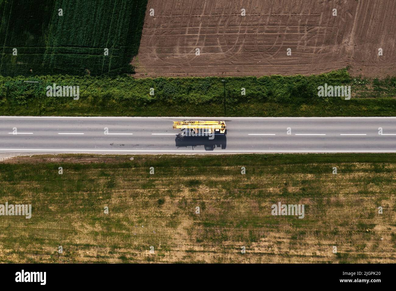 Kranwagen oder Boom-Truck auf der Straße durch die Landschaft, Luftaufnahme von Drohne pov, direkt darüber Stockfoto