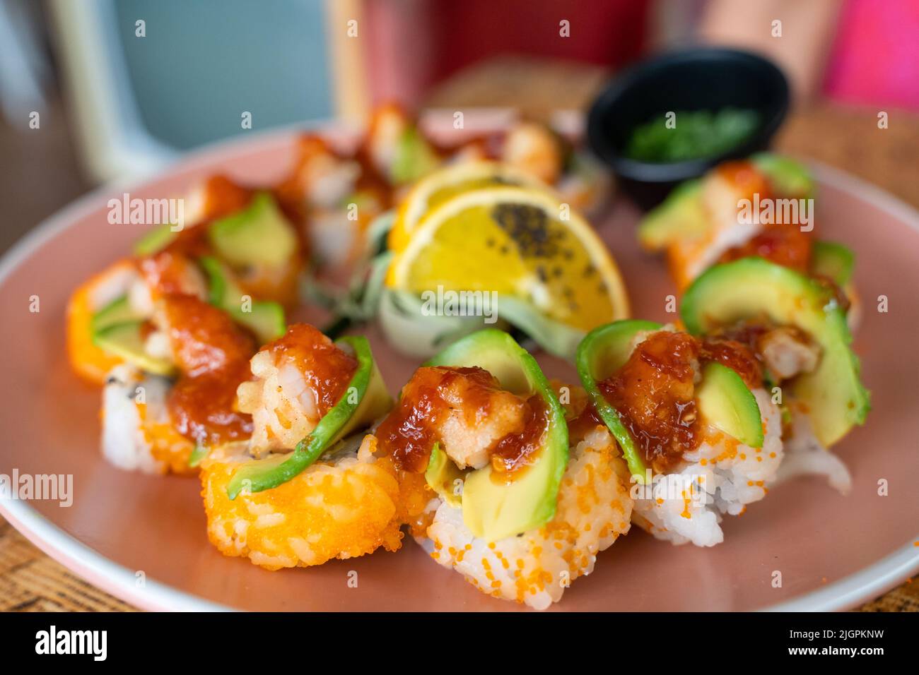 Kalifornischer Sushi-Rollteller mit Avocado, Garnelen und würziger Sauce darauf. Gourmet Food Restaurant Konzept Stockfoto