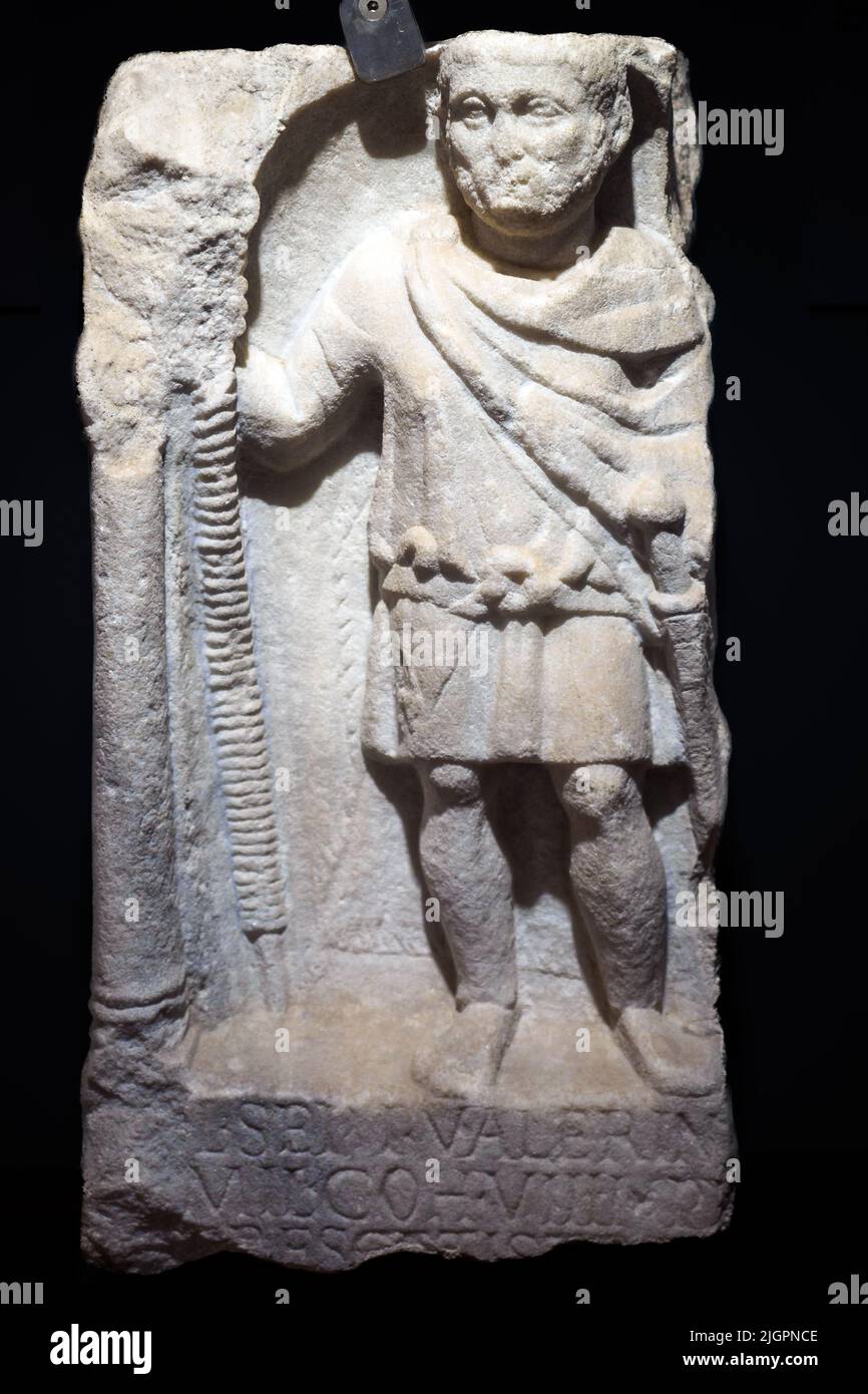 Grabaltar von Lucius Septimius Valerinus, Prätorianer der Kohorte von 9., dargestellt in Militärkleidung: Eine kurze Tunika, die an der Taille durch einen Gürtel gebunden ist, ein Umhang und die beiden für die Prätorianer typischen Waffen, das Pilum, ein langer Wurfspeer und das Gladium, ein kurzes Schwert. Rom, Via Salaria, Hypogeum der Via Livenza, erste Hälfte des 3.. Jahrhunderts n. Chr. - Nationales Römisches Museum - die Bäder des Diokletian - Rom, Italien Stockfoto