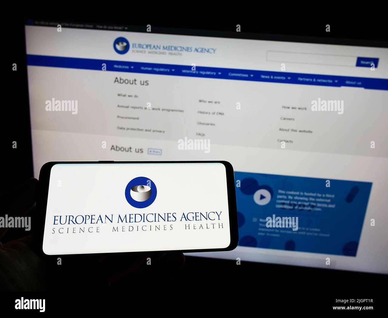 Person, die das Smartphone mit dem Logo der Europäischen Arzneimittel-Agentur (EMA) auf dem Bildschirm vor der Website hält. Konzentrieren Sie sich auf die Telefonanzeige. Stockfoto