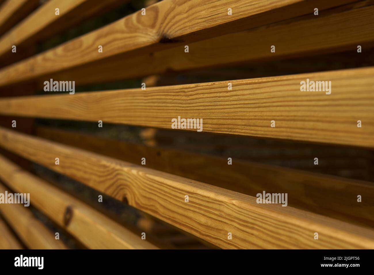 Seitenansicht einer Wand aus braunen Holzbalken in einem Pavillon in der Natur. Die Schönheit der Geometrie. Abstrakter Holzhintergrund. Das natürliche Holzbaumaterial für die Veredelung. Material mit Holzstruktur. Stockfoto