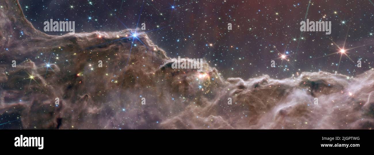 Die ersten Aufnahmen des James Webb Weltraumteleskops – die höchste Auflösung eines NASA-Verbundbildes, das die kosmische Kliffregion des Carina-Nebels zeigt. Dieses Bild, das gleichzeitig in Nahinfrarot und Mid-Infrared aufgenommen wurde, zeigt bisher unsichtbare Bereiche der Sterngeburt. Die Region ist tatsächlich der Rand eines riesigen, gasförmigen Hohlraums, der etwa 7600 Lichtjahre entfernt ist. Das Gebiet wurde durch die intensive UV-Strahlung und die Sternwinde massiver, heißer, junger Sterne, die sich über dem gezeigten Gebiet befinden, aus dem Nebel erodiert. 12. Juli 2022 Quelle: NASA, ESA, CSA und STScI / Alamy Live News via Digitaleye Stockfoto
