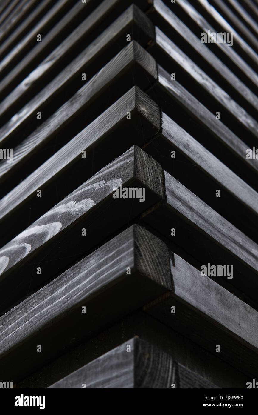 Schwarze horizontale Holzstäbe. Seitenansicht einer dekorativen Wand. Die Ecke des Pavillons. Foto mit vertikaler Ausrichtung. Wunderschöne Geometrie. Dekorative Holzstruktur. Das natürliche Holzmaterial. Stockfoto