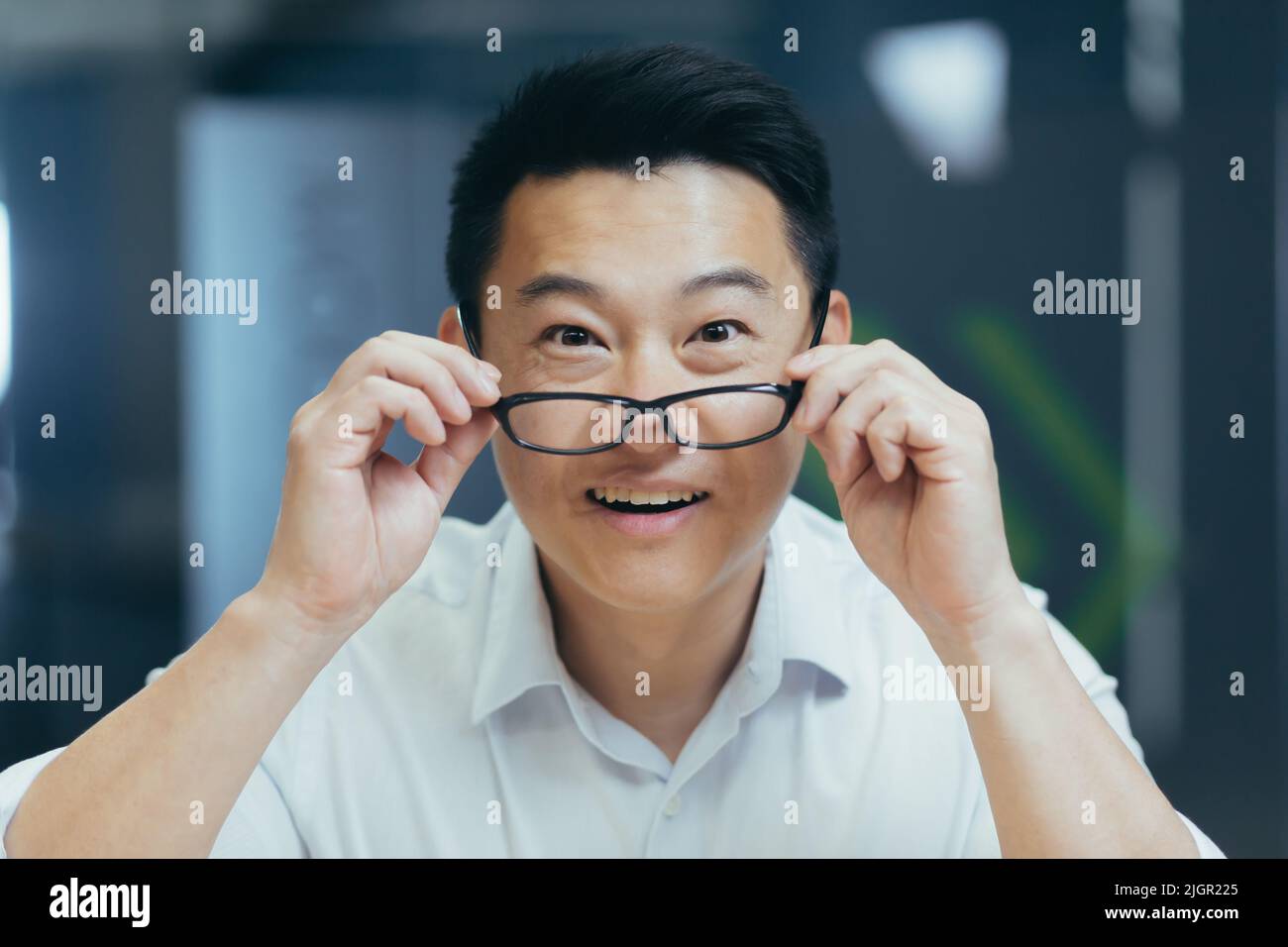 Überrascht asiatische Mann schießt Brille schockiert Blick auf Kamera. Fröhliches Lächeln freut sich. Schauen Sie sich Monitor-Bildschirm Webcam-Ansicht. Erstaunt Nahaufnahme Porträt. Gesicht hübscher Mann Büroangestellter Wow Ausdruck Stockfoto