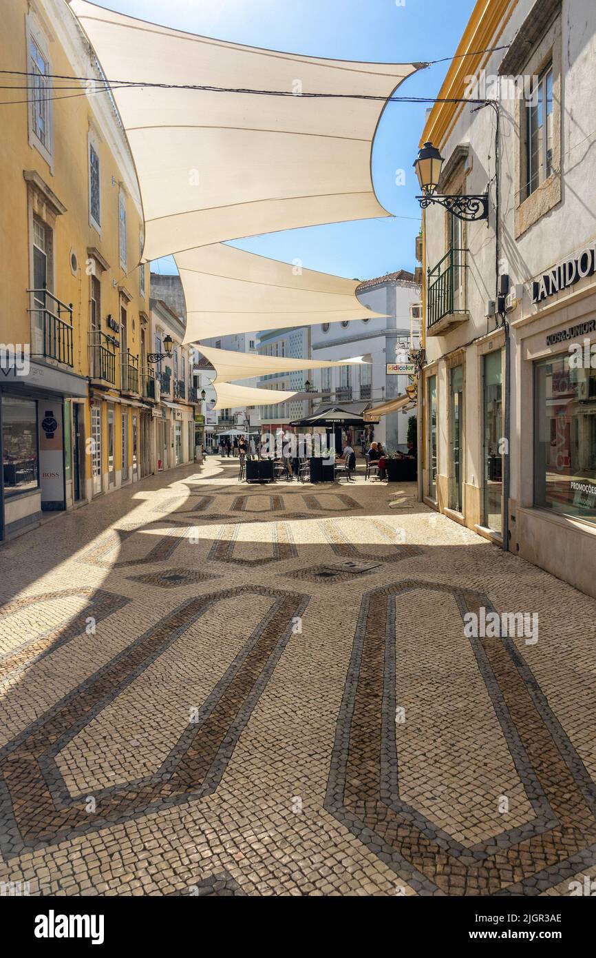 Geschäfte und Restaurants auf der Rua Ivens Eine Fußgängerzone im Stadtzentrum von Faro die Algarve Portugal mit großen Sonnenschirmen auf der anderen Straßenseite Stockfoto