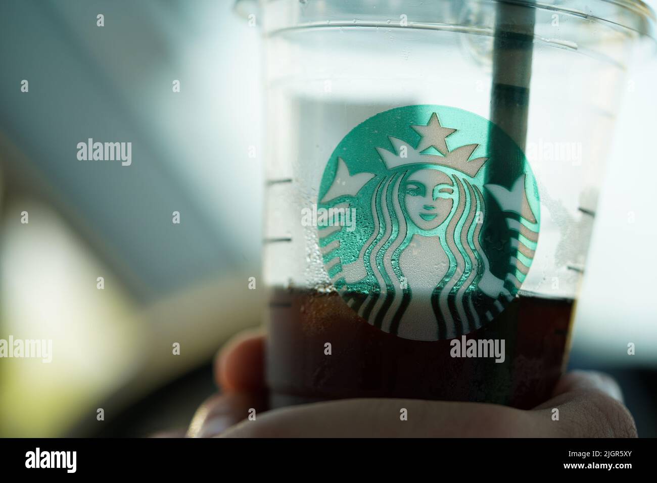 Eine Person, die eine Starbucks Kaffeetasse im Auto hält. Stockfoto