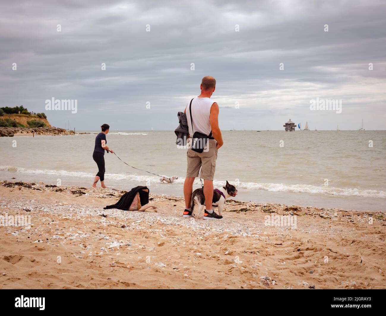 La rochelle, Frankreich, Juli 2022. Eine Frau geht mit ihrem Hund am Strand von La Rochelle, mit dem Meer und den Schiffen im Hintergrund Stockfoto