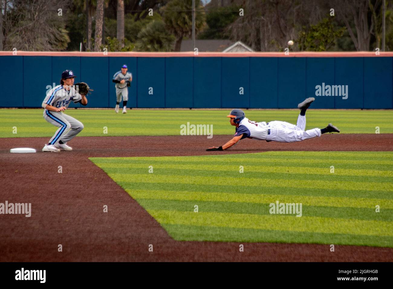 Bei dem Versuch, die zweite Basis zu stehlen, ist ein College-Baseballspieler zu langsam, um den Ball zum Fang des zweiten Basemans in Costa Mesa, CA, zu schlagen. Stockfoto