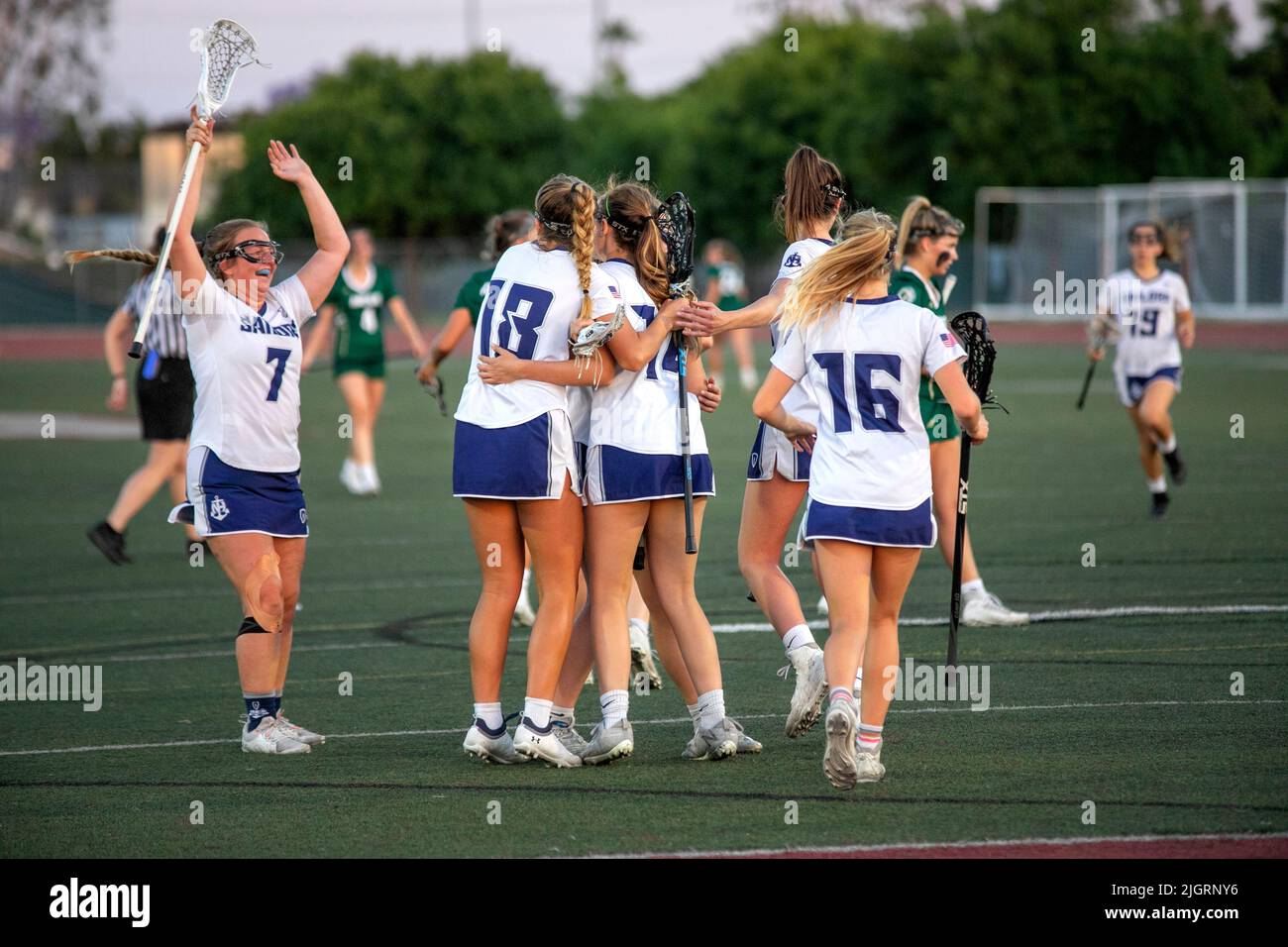 Umarmende High School Mädchen feiern ein Lacrosse-Spielziel in einem Downey, CA, Stadion. Stockfoto