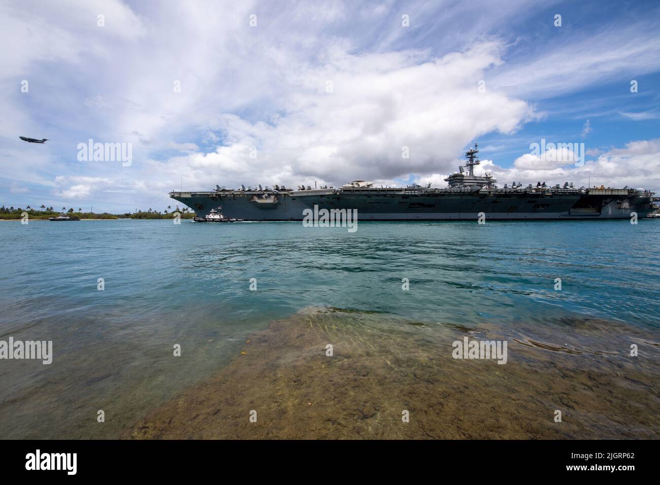 220711-N-NB544-1065 PEARL HARBOR (11. Juli 2022) Eine US-Luftwaffe C-17 fliegt vorbei, als der Flugzeugträger USS Abraham Lincoln (CVN 72) der Nimitz-Klasse Pearl Harbor verlässt, um am 11. Juli die auf See gelegene Phase von Rim of the Pacific (RIMPAC) 2022 zu beginnen. 26 Nationen, 38 Schiffe, vier U-Boote, mehr als 170 Flugzeuge und 25.000 Mitarbeiter nehmen vom 29. Juni bis zum 4. August an RIMPAC in und um die Hawaii-Inseln und Südkalifornien Teil. RIMPAC, die weltweit größte internationale maritime Übung, bietet eine einzigartige Ausbildungsmöglichkeit und fördert und pflegt dabei kooperative Beziehungen untereinander Stockfoto