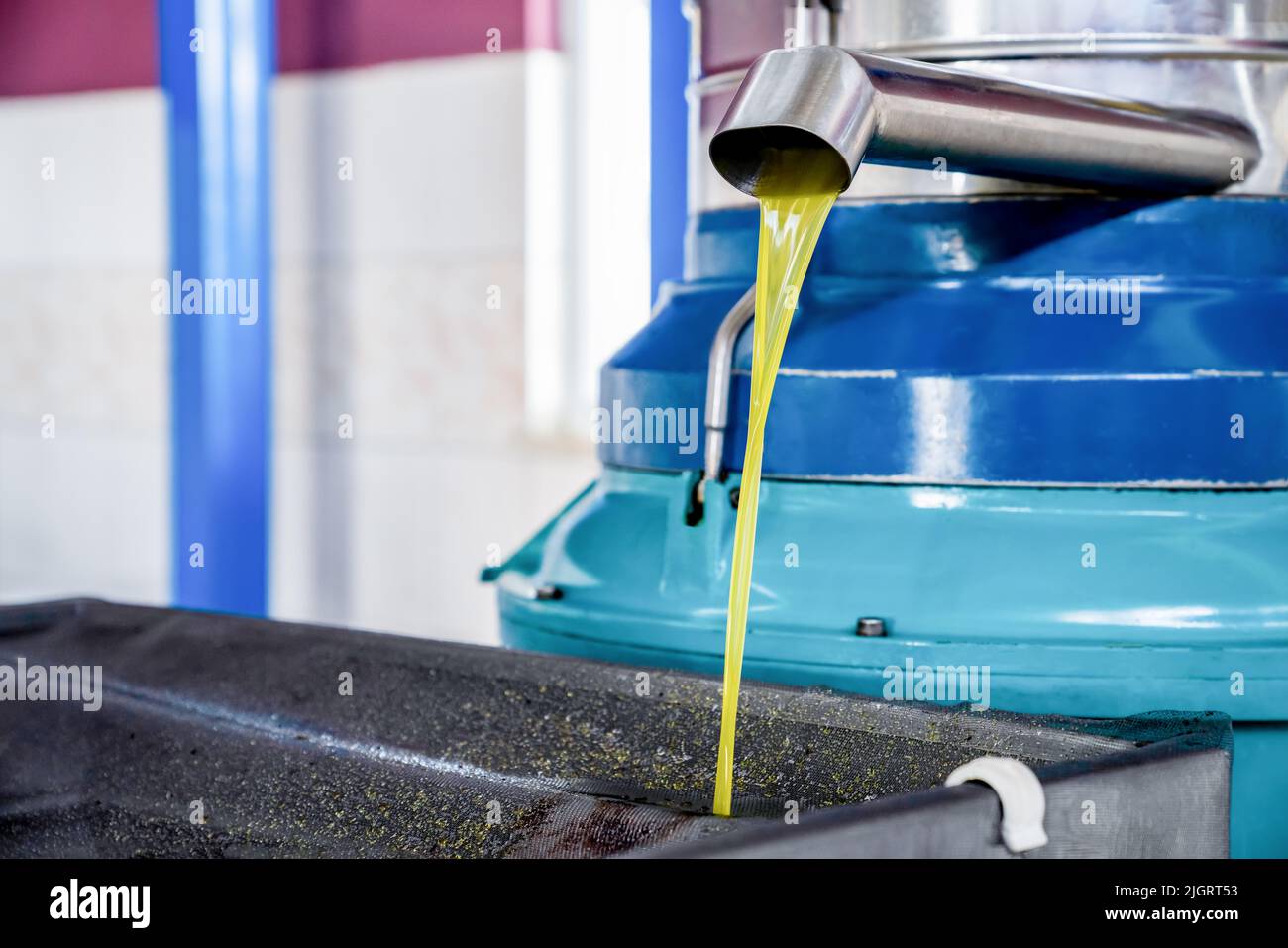 Olivenöl gießt aus dem Hahn der Spinnmaschine. Produktionsprozess von nativem Olivenöl extra in der Fabrik. Nahaufnahme Stockfoto
